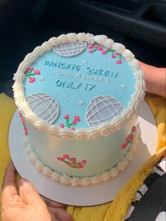 a blue and white cake sitting on top of a table next to a persons hand