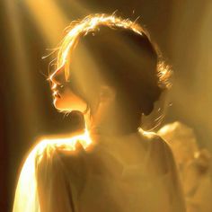 a woman is shown in the sunlight with her head turned to the side and light shining through