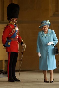 queen elizabeth and the duke of edinburgh stand in front of an official guard at buckingham palace