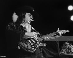 two men playing guitars on stage with one man wearing a hat and the other holding a guitar