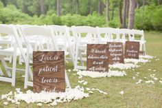 the chairs are lined up with white petals on them and signs that read love is patient love is family