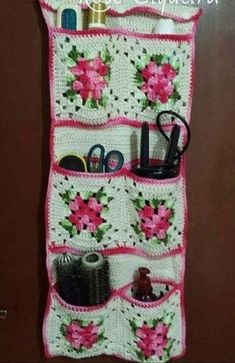 a crocheted purse hanging on the wall with scissors and other items in it