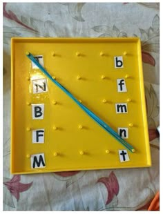 a yellow tray with letters on it and a blue toothpick in the middle