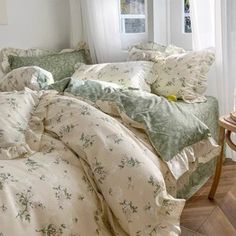 an unmade bed with green and white comforter in a bedroom next to a window