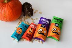 five candy bars with faces on them next to an orange pumpkin and some peanutshells