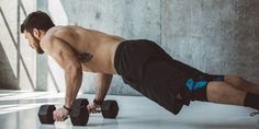 a shirtless man doing push ups with two dumbbells