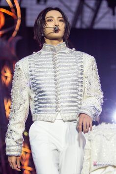 a man in a white suit and black nose ring on the catwalk at a fashion show