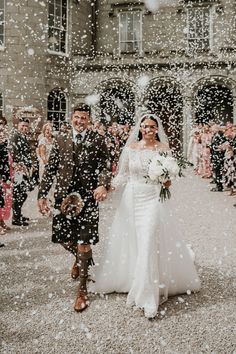 a bride and groom walking through the snow with confetti falling all around them