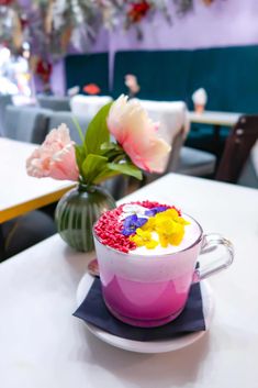 a cup filled with cake sitting on top of a white table next to a vase full of flowers