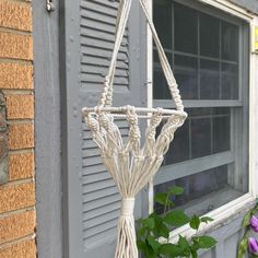 an old basketball hoop hanging from the side of a building with flowers in front of it