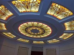 the ceiling in this room is decorated with stained glass and gold accents, along with decorative lighting