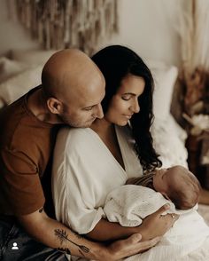 a man and woman holding a baby in their arms