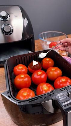 tomatoes being cooked in an air fryer on a wooden table next to a toaster