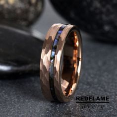 a wedding band with an opal inlay is shown on top of a granite surface