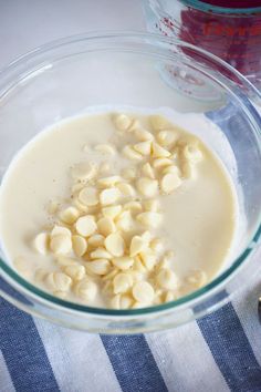 a glass bowl filled with food next to a jar of liquid and a wooden spoon