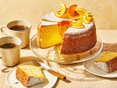 there is a cake with orange slices on it and two cups of coffee next to it