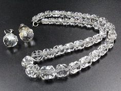 "DESCRIPTION: Transport yourself to the roaring 1920s with this exquisite antique jewelry set, a testament to the opulence of the Art Deco era. The necklace, a masterpiece of design, features a symphony of rock quartz crystal beads gracefully strung together and secured with a sterling silver clasp bearing the hallmark \"BB\" and \"STERLING.\" Complementing this timeless piece are the stud earrings, a perfect match to the necklace's elegance. In excellent condition, the set is an antique treasure, with a minor residue of glue delicately hinting at its rich history. The necklace, boasting a spring ring clasp, measures a dainty 16\" with beads ranging from 6mm to 12mm, while the earrings, secured with a screw-back clasp, exhibit a charming 15mm diameter. This Art Deco ensemble is a captivati Vintage Diamond Cut Jewelry For Wedding, Vintage Diamond Cut Necklace For Formal Occasions, Vintage Diamond Cut Wedding Jewelry, Vintage Wedding Jewelry With Diamond Cut, Formal Faceted Beads Round Necklace, Formal Round Necklace With Faceted Beads, Formal Round Necklaces With Faceted Beads, Round Faceted Beads Necklace For Formal Occasions, Antique Diamond Cut Necklaces For Weddings