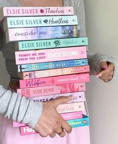 a woman is holding a stack of books in her hands while wearing a pink skirt