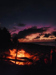 a person sitting in front of a fire on the beach