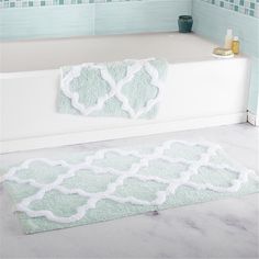 a white bath tub sitting next to a blue tiled bathroom wall with a rug on the floor