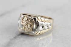 a gold and silver ring with a lion head on it's center band, sitting on a marble surface