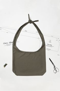 a gray bag sitting on top of a white table next to scissors and other items