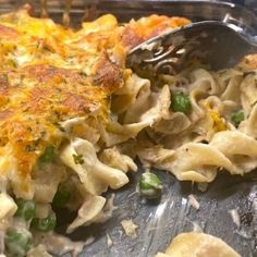 a casserole dish with peas and cheese being eaten by a fork from a pan