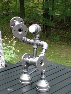 a metal faucet sitting on top of a wooden table next to a forest