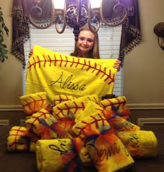 a girl holding up a softball towel with the name alisha on it in front of a window