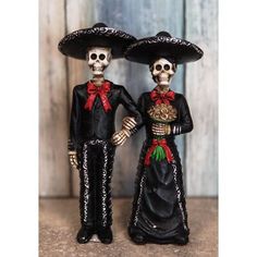 two skeleton figurines wearing sombrero hats and holding hands with each other