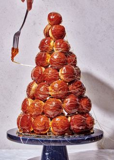 a person holding a fork over a pile of donuts on a blue cake plate