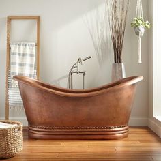 a bath tub sitting on top of a hard wood floor next to a basket filled with flowers