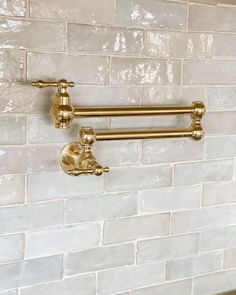 two brass faucets on a white brick wall