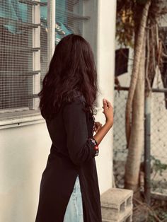 a woman standing in front of a building with her back to the camera and looking at something