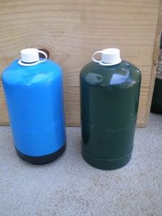 two blue and green water bottles sitting next to each other