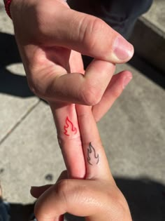 two people holding hands with tattoos on their fingers