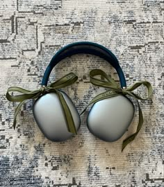 two silver and green headphones on top of a rug with a ribbon around the ears