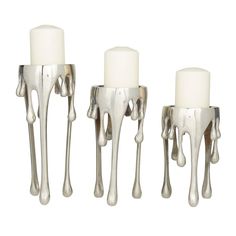 three silver candles with white wax dripping from them