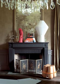 a living room with a fire place, chandelier and pictures on the mantle