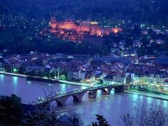 an aerial view of a city at night with lights on the buildings and water below