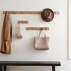 a hat, coat rack and purse hanging on a wall with the words west elm written below it