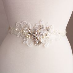 Ivory Bridal belt  Bridal sash Wedding dress belt sash Flower Pearl Bridal  belt Wedding Accessories Bridal accessories Bridal sash with pearls and crystals WEDDING SASH BELT DETAILS Bridal sash, perfect for vintage inspired or one very romantic wedding.  Color: light ivory /ivory/clear/silver Lace accent size: approx 9-9.5 inches, width approx 3 inches. Light ivory beaded lace. Materials: lace, ivory faux pearls, clear  crystals, seed beads. Satin ribbon in ivory 25mm x 260 cm, for you to tie a bow at the back. Lace headpieces and other sashes available in our shop please check. Simple packaging as in stock at this moment. Wedding  Belts: https://www.etsy.com/uk/shop/DonataleFlowers4You? section_id=14095241&ref=shopsection_leftnav_8 Lace Headpieces: https://www.etsy.com/uk/shop/DonataleAc Elegant Wedding Sash With Belt, Elegant Wedding Sash With Matching Belt, Elegant Bridal Sashes For Bride, Elegant Bridal Sashes, Elegant Bridal Belt With Sashes For Wedding, Elegant Bridal Belt With Sashes For Bride, White Bridal Belt For Bride, Elegant White Bride Sashes, White Embroidered Belt For Party