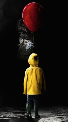 a person in a yellow raincoat is holding a red balloon