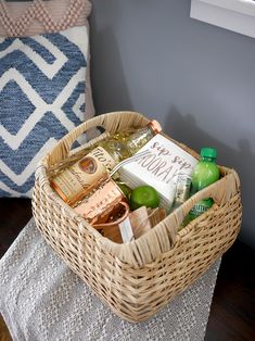 a wicker basket filled with drinks on top of a table next to a pillow