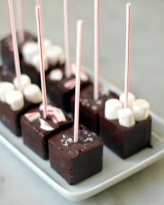 chocolates with marshmallows and candy sticks on a white plate sitting on a table