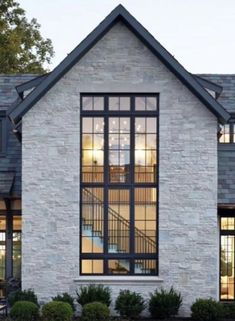 a white brick house with large windows and black shutters on the front door is lit up at night