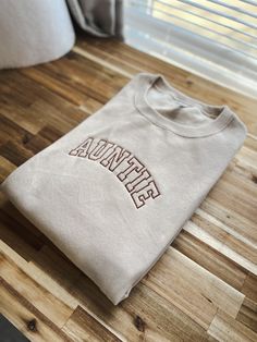 Us aunties/tias deserve a comfy and cozy sweatshirt too! Not an auntie?? Feel free to have a custom request for your sweatshirt! Just type it into the blank text box .🤍 This sweatshirt sports an athletic font that is giving cool aunt vibes. Throw this classic crew on and be ready to take on your exhausting day of being an auntie! Design measurements are roughly 7” long by 2.5” tall for sizes Small to XL. Sizes 2X - 4X have a design size of roughly 10" long by 4" tall. All sweatshirts are unisex One Word Sweatshirts, Auntie Era Sweatshirt, Auntie Embroidered Sweatshirt, Auntie Clothes, Cool Aunt Aesthetic, Auntie Outfits, Trending Sweatshirts, Aunt Vibes, Country Fall Outfits