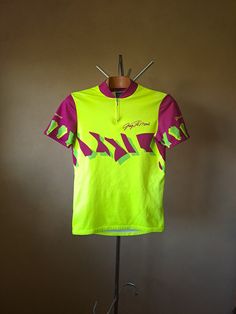 Vintage cycling jersey made in Italy by Tomasso in the early 90's. Features printed Greg LeMond signature above heart. About average thickness. Material is probably 100% polyester, maybe a bit of Nylon mixed in. Size would be a looser L in men's/XXL in women's by measurement, tag says 4. Condition 8/10: In very good shape, just small signs of previous use visible, like a couple of small pull remnants and slightly faded back. This cycling top has three pockets on the back and a short zipper on th Fitted Short Sleeve Jersey For Sports Events, Fitted Graphic Print Jersey With Short Sleeves, Fitted Short Sleeve Jersey With Graphic Print, Fitted Yellow Tops For Sports Events, Fitted Short Sleeve Jersey, Greg Lemond, Vintage Cycling Jersey, Vintage Cycling, Short Zipper