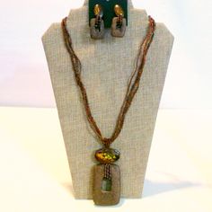 This Lovely Demi Parure Consists Of A Necklace And Matching Pierced Drop Earrings. The Set Is Fashioned In Different Shades Of Brown Seed Beads With A Dyed Shell Top At The Pendant And Earrings And What I Believe Is Lava Stone Drops. The Earrings Are Still On Their Original Card That Says Made In The Philippines. The Necklace Measures 24" In Length And The Pendant Has A Drop Of 3 7/8". The Earrings Feature A Post Back For Pierced Ears And Are 2" In Length. Bohemian Brown Rectangular Jewelry, Bohemian Brown Rectangular Necklace, Brown Artisan Jewelry With Dangling Beads, Artisan Brown Jewelry With Dangling Beads, Costume Jewelry With Colorful Beads In Brown, Colorful Beaded Brown Costume Jewelry, Brown Costume Jewelry With Colorful Beads, Bohemian Brown Fair Trade Jewelry, Brown Fair Trade Jewelry For Festivals