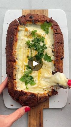 someone is cutting into a pizza with cheese and herbs